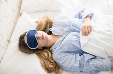Frau schläft mit Schlafmaske im Bett