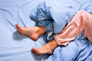 Füße im Bett halb von einer Bettdecke bedeckt